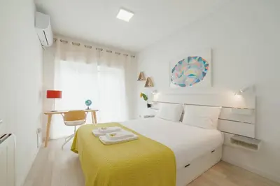 a white bedroom with a bed with a yellow blanket at Santa Catarina Apartment by Hosty in Porto