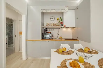 a kitchen with white cabinets and a table and chairs at Santa Catarina Apartment by Hosty in Porto