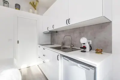 a kitchen with white cabinets and a sink at Studio de luxo no Porto - T0 in Porto