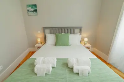 a bedroom with a large bed with two white chairs at Bonfim Premium by Hosty in Porto