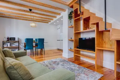 a living room with a couch and a tv and a table at Cais das Pedras Duplex by Cozy Stay in Porto