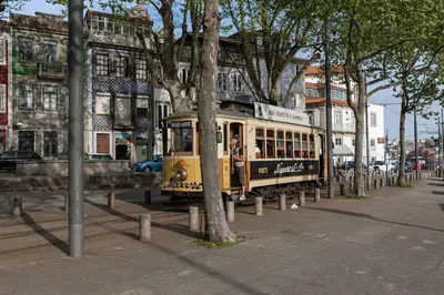 a trolley car on a city street with trees at Cais das Pedras Duplex by Cozy Stay in Porto