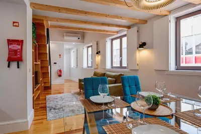 a living room with a glass table and blue chairs at Cais das Pedras Duplex by Cozy Stay in Porto