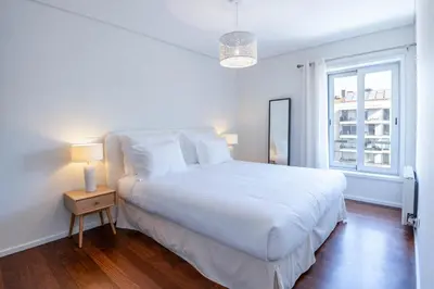 a white bedroom with a large bed and a window at Cedofeita Sunny Apartment - Balcony & Parking in Porto