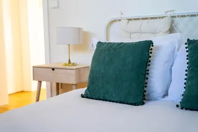 a bed with two green pillows and a lamp on a table at Porto Heights by LovelyStay in Porto