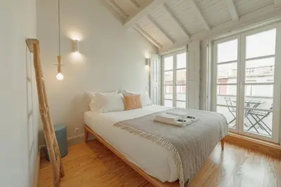 a white bedroom with a bed and a large window at Deluxe Duplex by Hosty in Porto