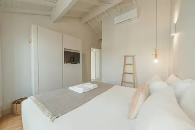 a white bedroom with a large white bed and a ladder at Deluxe Duplex by Hosty in Porto