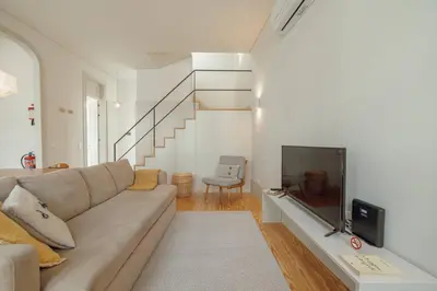 a living room with a couch and a staircase at Deluxe Duplex by Hosty in Porto