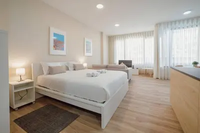 a white bedroom with a large bed and a couch at Trindade Deluxe by Hosty in Porto