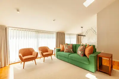 a living room with a green couch and two chairs at Savvy Signature Apartments in Porto
