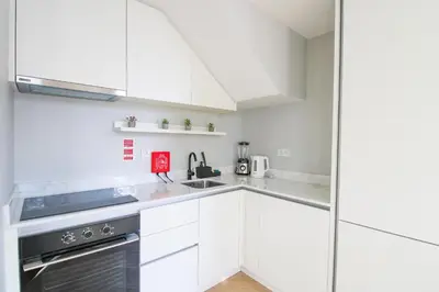 a white kitchen with white cabinets and a sink at Saudade do Porto in Porto