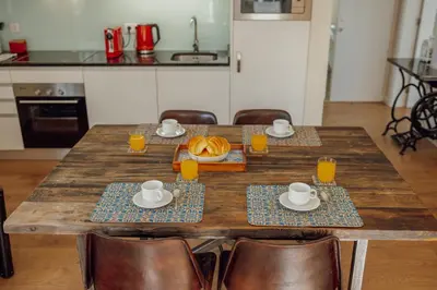 a wooden table with two plates of food and orange juice at Rooftop Panoramic Batalha- PORTO in Porto