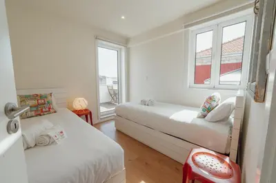 a bedroom with two beds and two windows at Rooftop Panoramic Batalha- PORTO in Porto