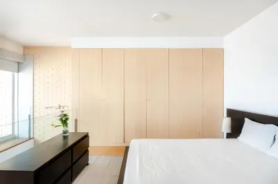 a bedroom with a white bed and a black cabinet at VIVA Stadium Residence Studios in Porto