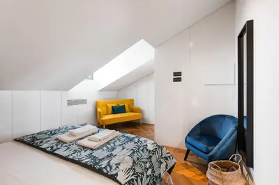 a bedroom with a bed and a yellow chair at Elegant Duplex Apt in Downtown by Lisbeyond in Porto