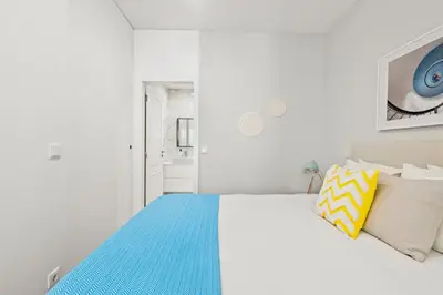 a white bedroom with a bed with a blue blanket at Almada Prime - Live in Porto in Porto
