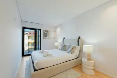 a white bedroom with a bed and a window at GuestReady - Comfortable stay in Porto in Porto