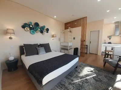 a bedroom with a large bed and a kitchen at Vista Bolhão Studio in Porto