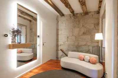 a living room with a white couch and a stone wall at Bandeiras in Porto