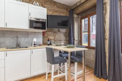 a kitchen with white cabinets and a table with chairs at Charming Studio with Garden in Porto in Porto