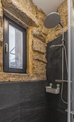 a bathroom with a stone wall and a shower at Charming Studio with Garden in Porto in Porto