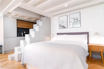 a white bedroom with a white bed and a staircase at Limehome Porto Rua 31 de Janeiro in Porto
