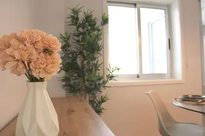 a white vase with flowers sitting on a table at Marquês City Center Flat in Porto