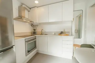 a white kitchen with white cabinets and a table at Modern Studio by Hosty in Porto