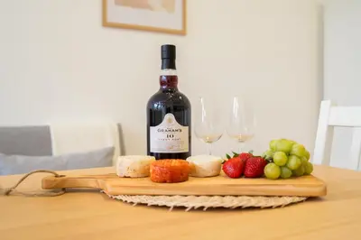 a bottle of wine on a cutting board with fruit and wine glasses at Host Wise - Santa Catarina Cosy Downtown in Porto