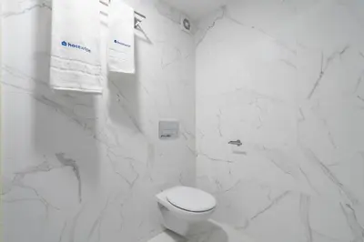a white bathroom with a toilet and white marble walls at Host Wise - Santa Catarina Cosy Downtown in Porto