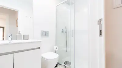a white bathroom with a toilet and a shower at Porto River Flat w/ Patio by LovelyStay in Porto