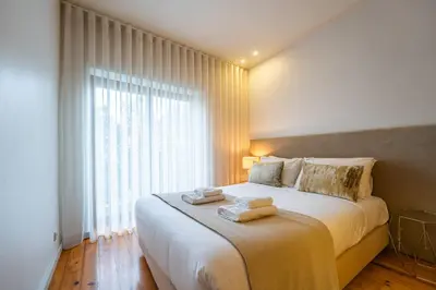 a bedroom with a large bed with two towels on it at Brittos Lapa Apartment in Oporto City Center in Porto