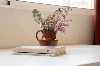 a vase with flowers and two books on a table at Jardim do Morro Apartment By Porto Stories in Vila Nova de Gaia
