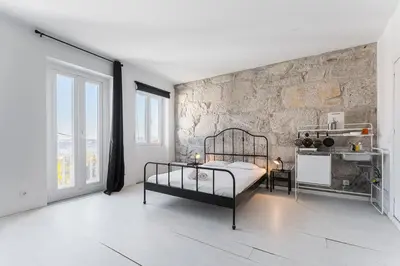 a bedroom with a bed and a stone wall at PortoNest Downtown Studios in Porto