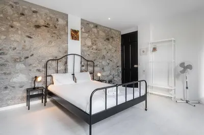 a bedroom with a bed and a stone wall at PortoNest Downtown Studios in Porto
