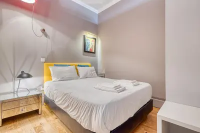 a bedroom with a bed with white sheets and a lamp at OPORTO GUEST Luxus Ildefonso in Porto
