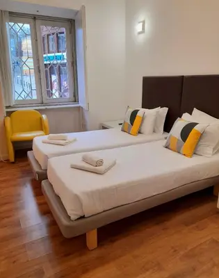 two beds in a room with a yellow chair at Clérigos Ville Porto Rooms in Porto