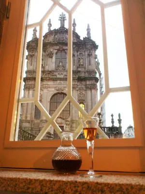 a glass of wine sitting in front of a window at Clérigos Ville Porto Rooms in Porto