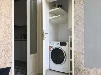 a washing machine in a kitchen next to a door at Central location with balcony & equipped kitchen in Porto