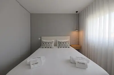 a bedroom with a large white bed with two pillows at FLH Boavista Woody Flats in Porto