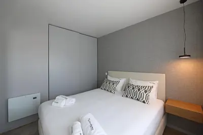 a bedroom with a large white bed with pillows at FLH Boavista Woody Flats in Porto