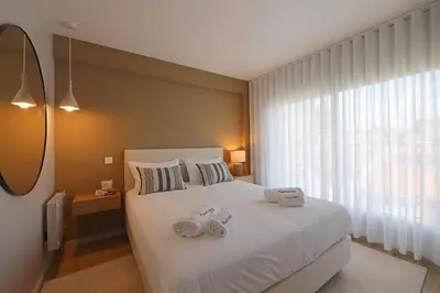 a bedroom with a white bed with two towels on it at FLH Boavista Woody Duplexes in Porto