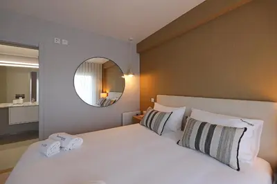 a bedroom with a large white bed with a mirror at FLH Boavista Woody Duplexes in Porto