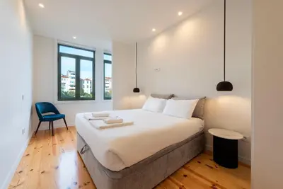 a bedroom with a large bed and a blue chair at Chic Porto Hideaway: Pool & Garden in Porto