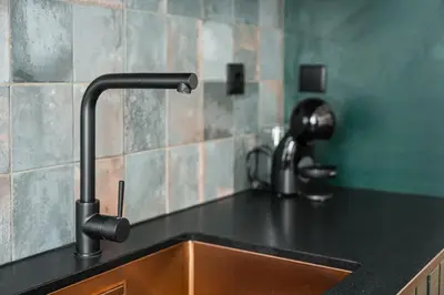 a kitchen sink with a black counter top and a faucet at GuestReady - Relaxing moment in a vibrant city in Porto