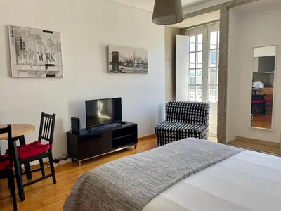 a bedroom with a bed and a tv and a chair at Douro River Cozy Flats in Porto