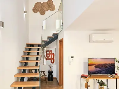 a staircase in a house with white walls and a television at VIVA Boho House Duplex in Porto