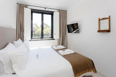 a white bedroom with a bed and a window at Liiiving in Porto - Casa Duque Apartments in Porto