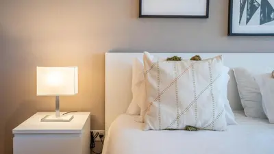 a white bed with a lamp on a night stand at Infante Cozy 1BR w Parking by LovelyStay in Vila Nova de Gaia