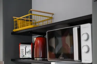 a shelf with a microwave and a yellow basket on it at GuestReady - Modern Home In Gaia in Vila Nova de Gaia
